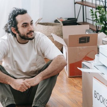 man sitting on floor beside boxes